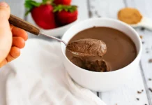 Decadent chocolate protein pudding topped with a sprinkle of cocoa powder, served in a glass dish.