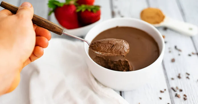 Decadent chocolate protein pudding topped with a sprinkle of cocoa powder, served in a glass dish.