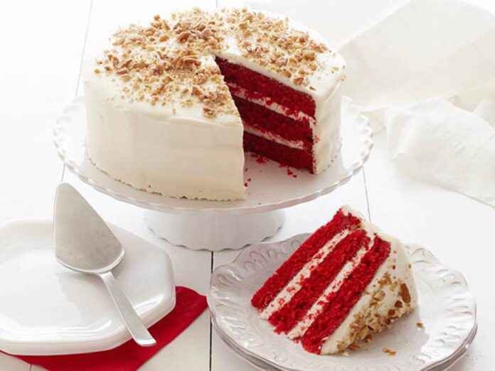 Delicious homemade red velvet cake topped with creamy frosting and chocolate shavings, perfect for birthdays and special occasions.