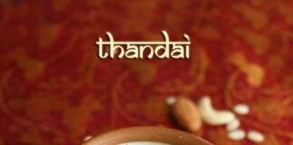 Refreshing Thandai Recipe - Traditional Indian Drink Blend with Almonds, Cardamom, and Saffron in a Glass Garnished with Pistachios and Rose Petals
