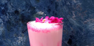 Delicious homemade rose milk served in a glass with petals garnishing the top, perfect for refreshing summer beverages.