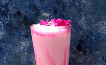 Delicious homemade rose milk served in a glass with petals garnishing the top, perfect for refreshing summer beverages.