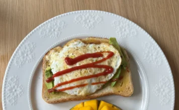Healthy and delicious breakfast toast recipe featuring slices of wholemeal sourdough bread topped with creamy almond cream cheese, fresh mango slices, a drizzle of maple syrup, and a sprinkle of organic matcha powder.